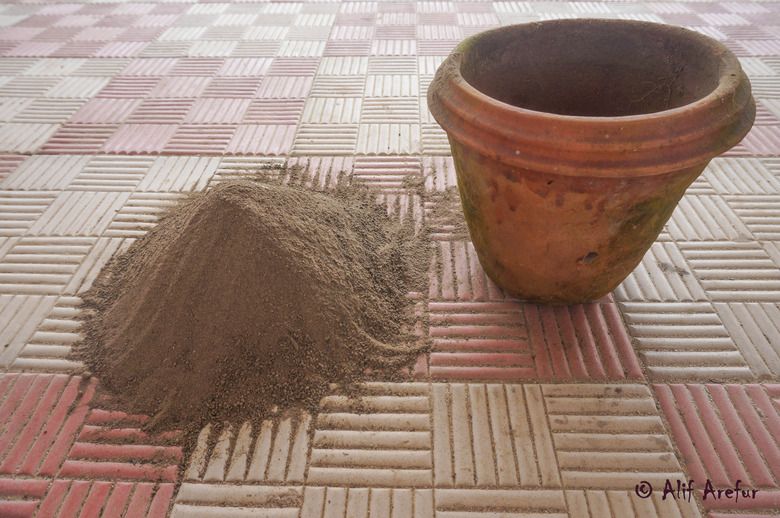 Sandy loam soil with compost fertiliser next to a garden pot.