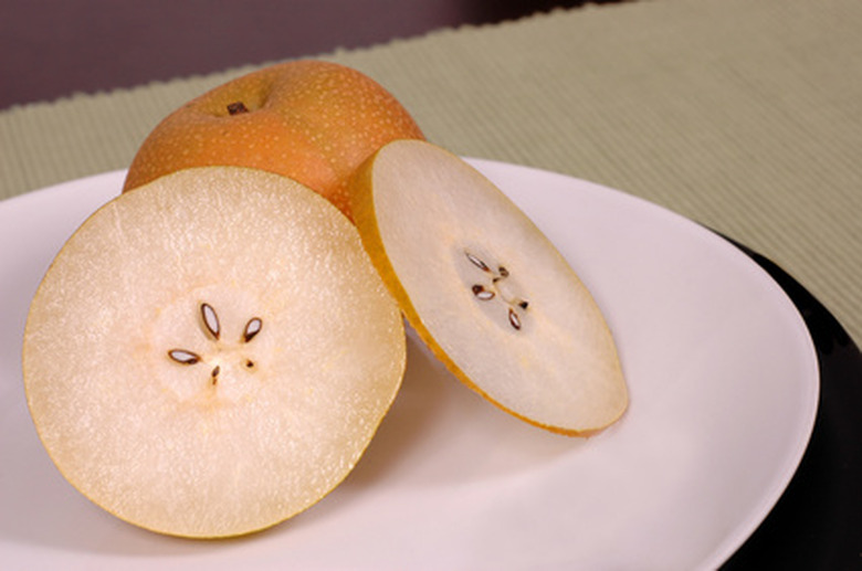 An Asian pear Pyrus pyrifolia with two slices laid out on a white plate.