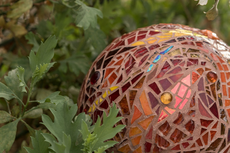 A close-up of a mosaic garden ball in shades of oranges