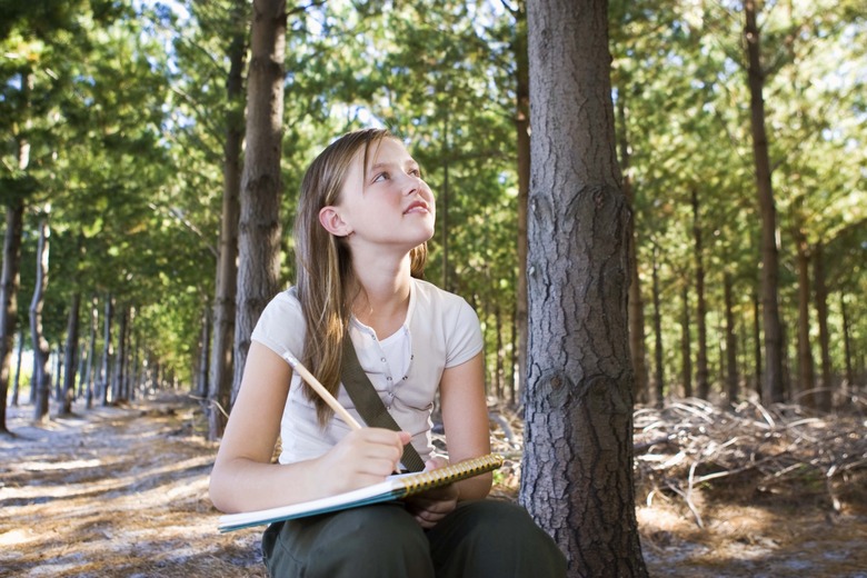 Girl writing in notebook in forest