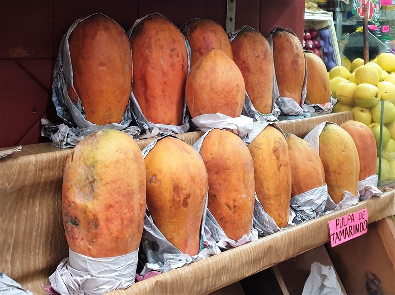 Two rows of ripe orange papayas on display at a market in Mexico.