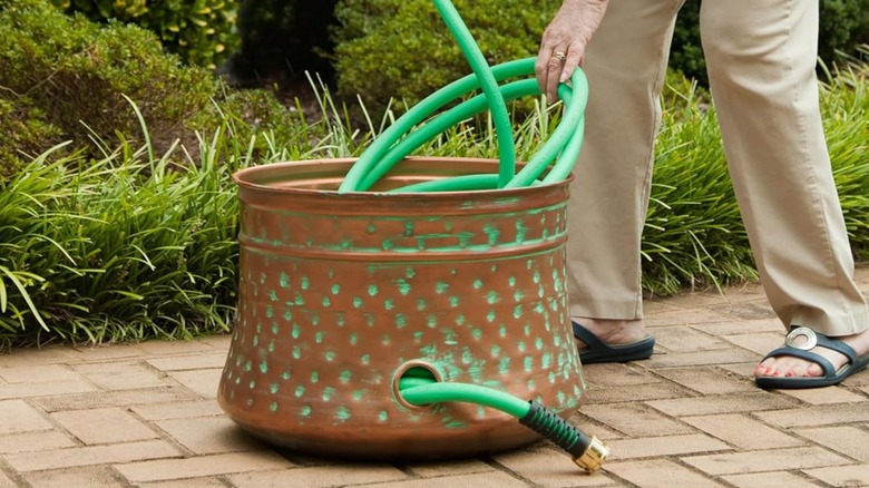 Woman stores hose in copper hose pot.