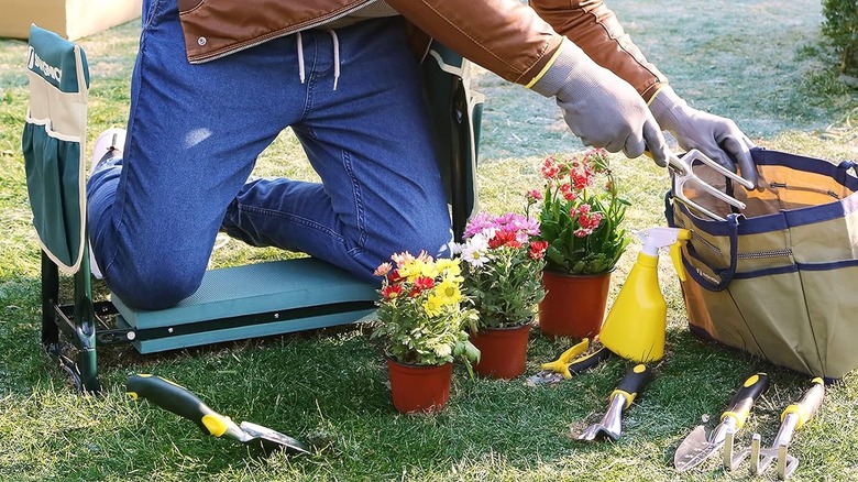 A man kneeling on a Songmics garden kneeler as he pulls out garden tools from a bag.