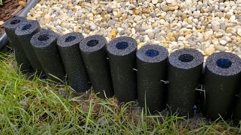 Sections of pool noodles line a garden bed.