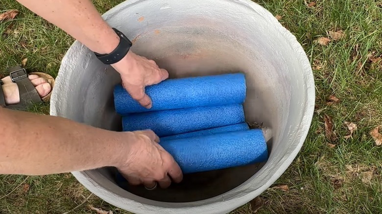 Woman fills large planter with cut up pieces of pool noodle.