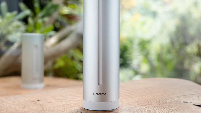 A silver Netatmo smart weather station on a wood surface