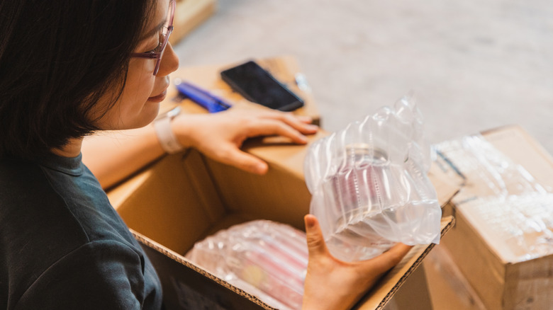 Woman looks at a jar wrapped in bubble wrap.