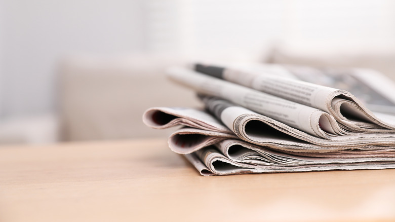 Stacks of newspapers sit on a pale table.