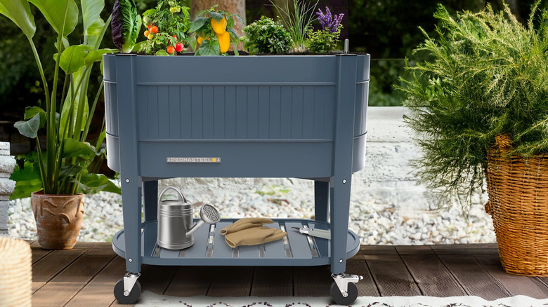 The Permasteel Elevated Garden Bed With Casters in blue, staged with plants on a deck