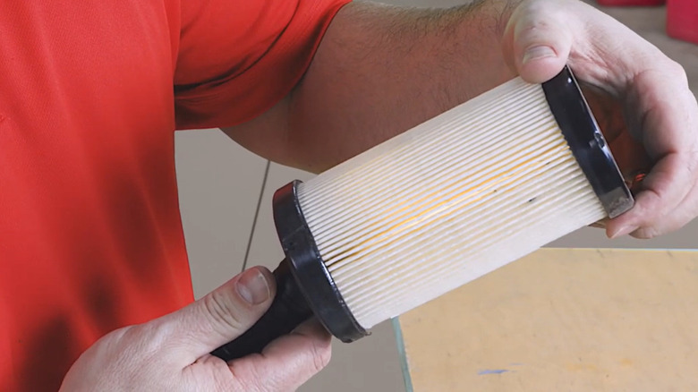 A mechanic examines an air filter for signs of damage or dirt.