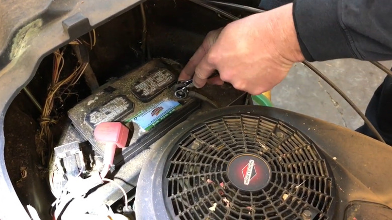 A man changes the battery in his riding lawn mower.