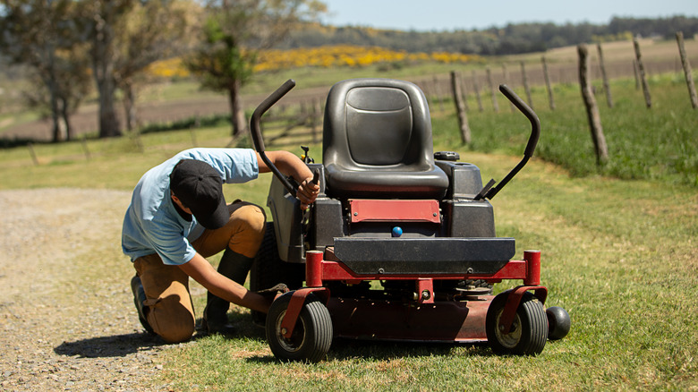 A man examines his riding mower.