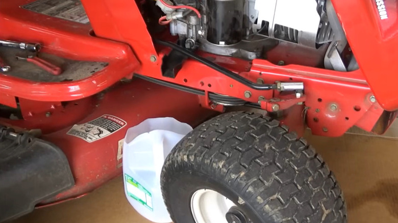 Oil is being drained and changed on a riding mower.