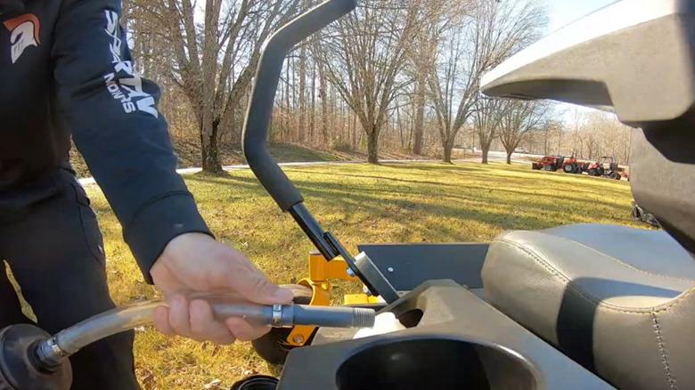 A man adds gas to his mower.