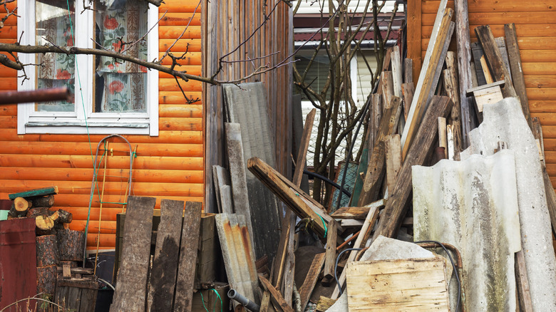 Construction waste and lumber leans against wood houses.