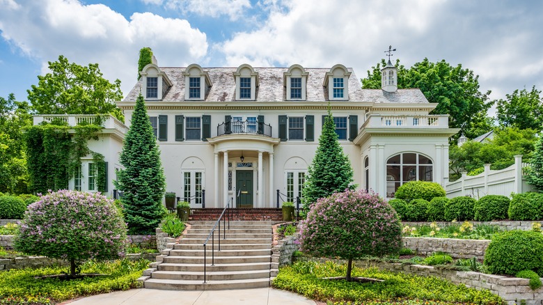 A large home boast multiple small flowering trees and shrubs.