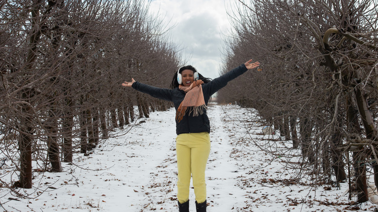 A cheerful woman stands in a fruit orchard in winter.
