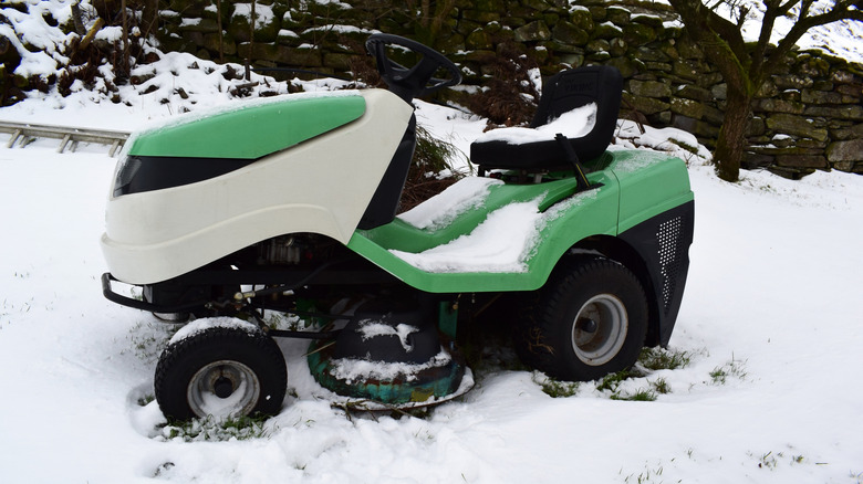 A riding lawn mower sits in the snow.