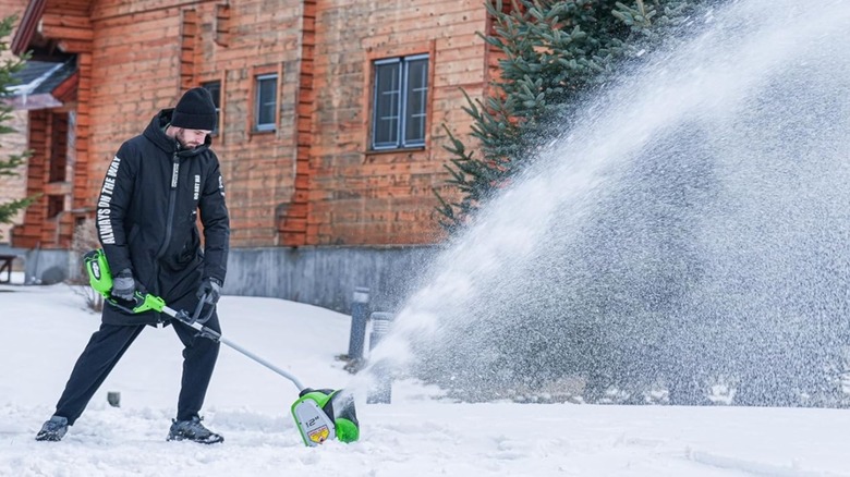 Man uses a Greenworks power snow shovel to remove snow.
