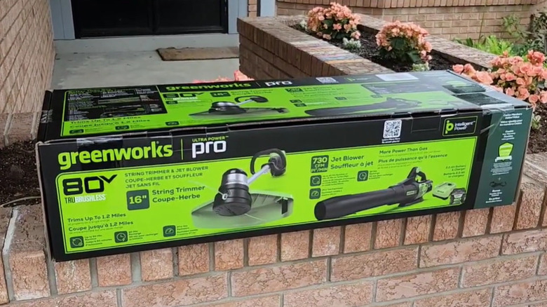 Green and black leaf blower, string trimmer, and battery pack against a white background