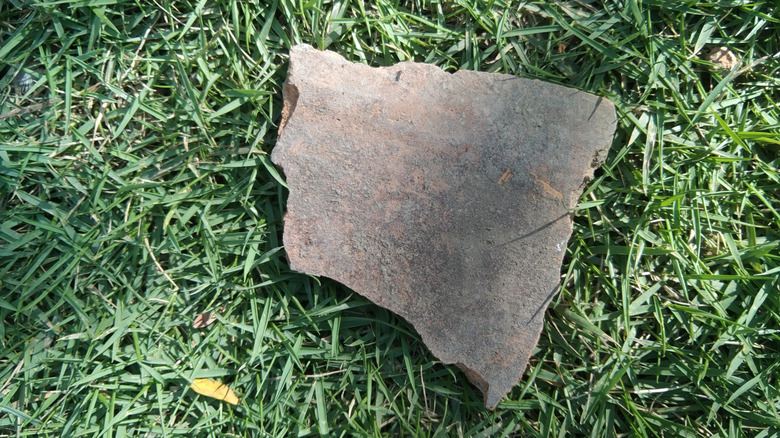 A large shard of tile lies on green grass.