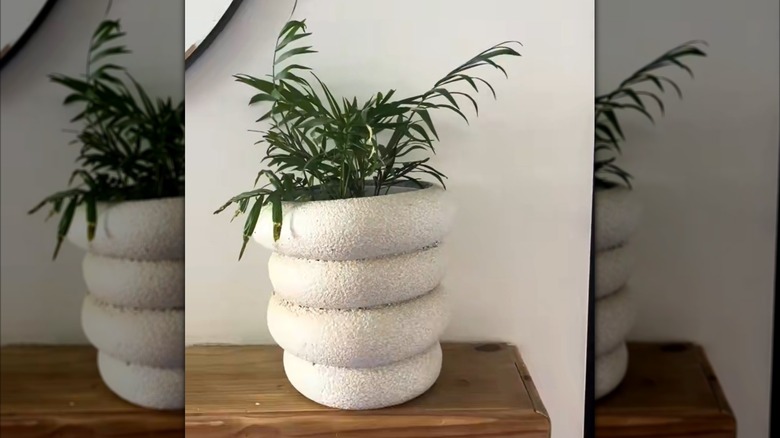A faux stone planter made of a pool noodle sits on a foyer table.
