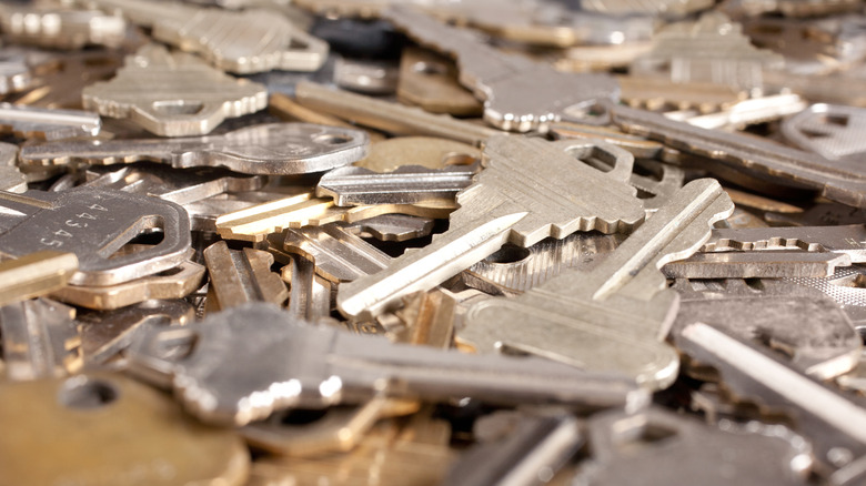 Loose silver and gold keys are layered on top of each other on a flat surface.