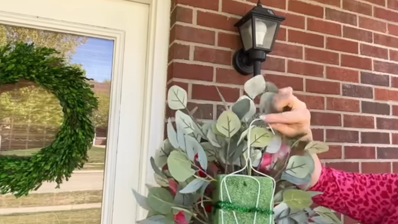 A wire hanger is used to hang up a faux floral arrangement.