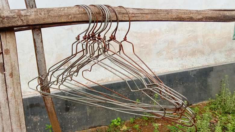 Wire hangers hang from a wooden outdoor structure.