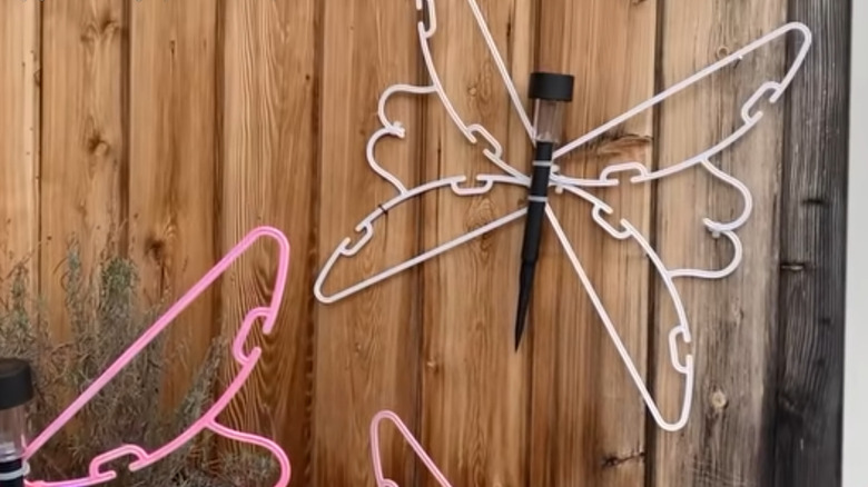 Butterflies made of plastic hangers decorate a fence.