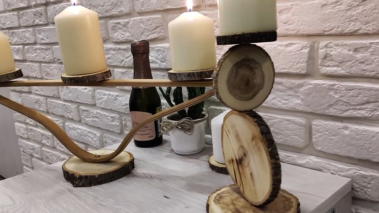 A wooden hanger has its hook removed and is mounted upside down to become a candle holder.