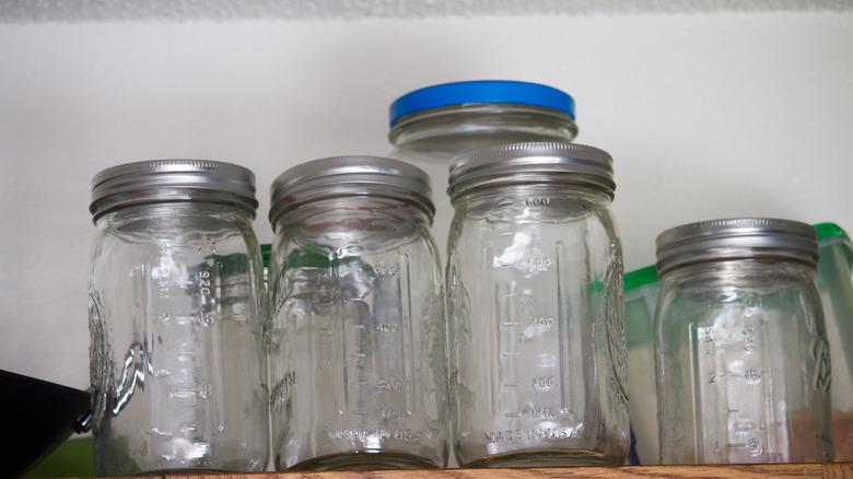 Unused mason jars and lids are on a shelf.