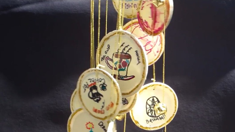 A woman holds a cute handmade wind chime featuring art drawn my her family.