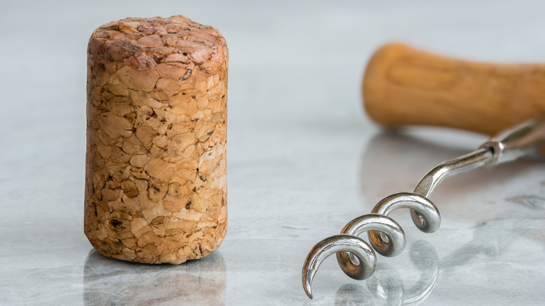 A wine cork sits next to a wine opener on the counter.