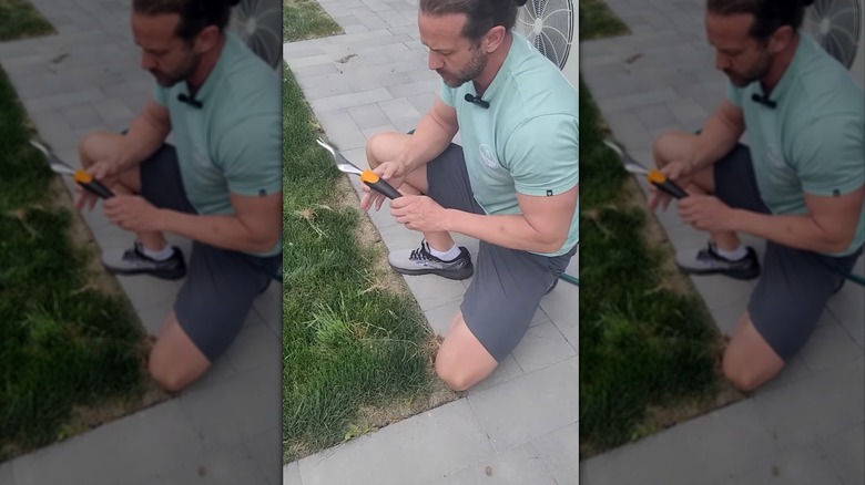 A man holds a Fiskars Ergo Weed Tool.