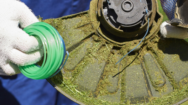 A man works to replace a broken weed eater string.