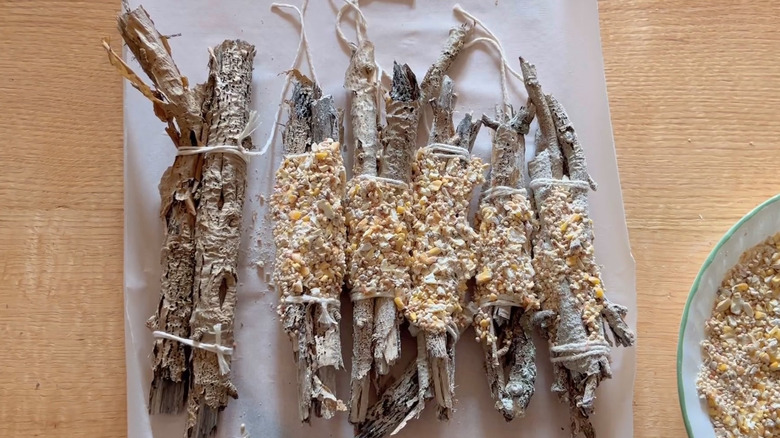 Bundles of sticks have been tied together with string and rolled in peanut butter and seeds.