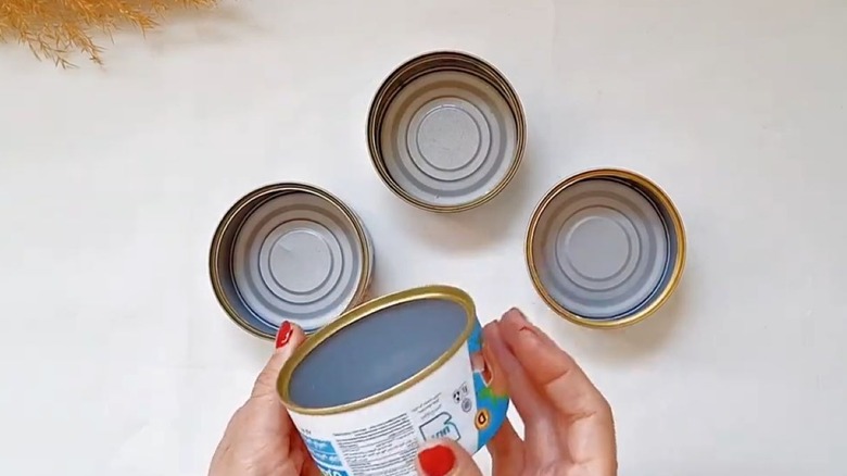 An open can of tuna is placed on a kitchen table.