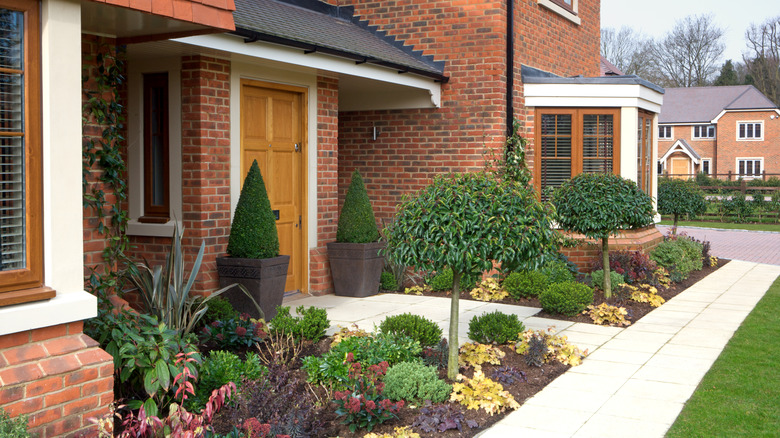 A well manicured front garden has formal plantings and no unsightly weeds.
