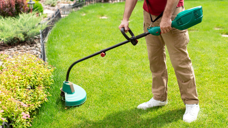 A man using an electric weed trimmer