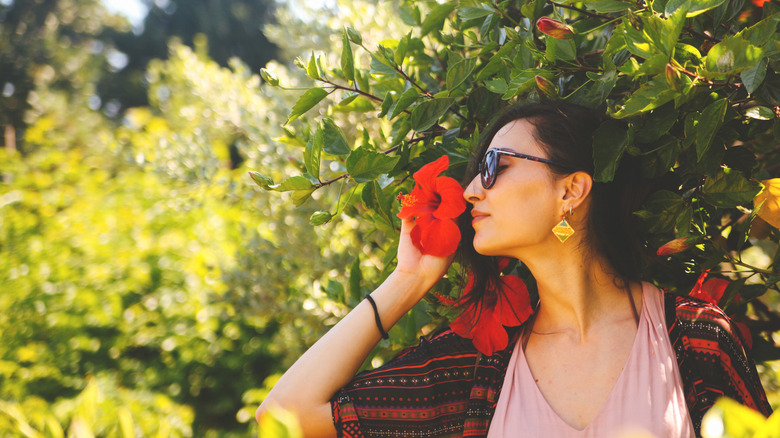 Woman smells hibiscus flower.