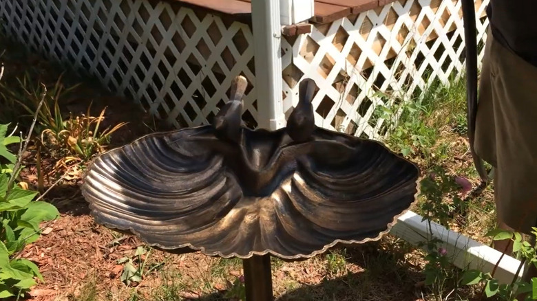 The 31-inch Alpine Birdbath with two birds sitting in a garden.