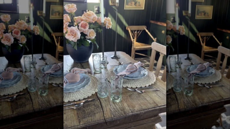 A set table in a black shed with pink roses on the table