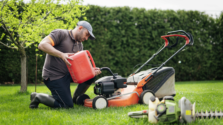 A gardener adds gas to a lawn mower.