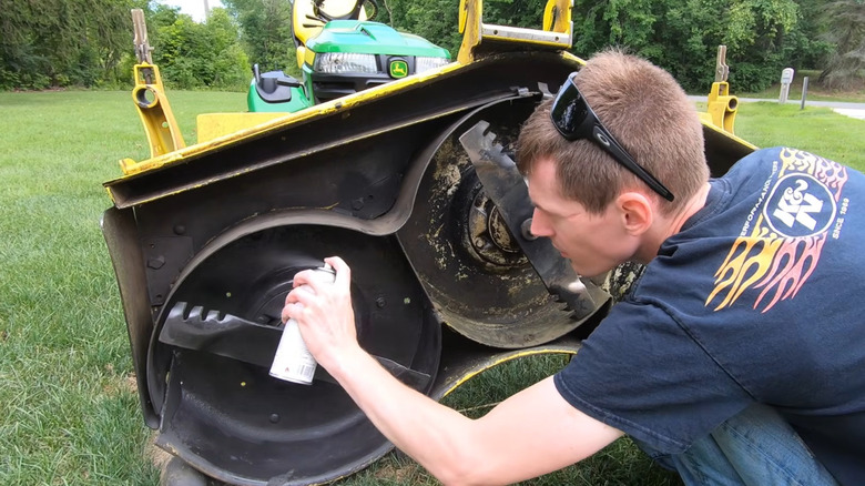 A man applies Magic Paints to the underside of a mower.