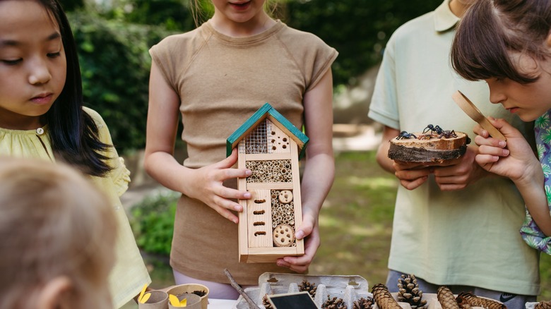 A girl holds a bee hotel she's just made.