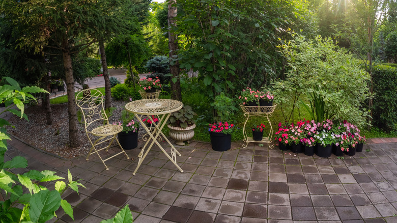 White wrought iron furniture and flower containers decorate a patio space.