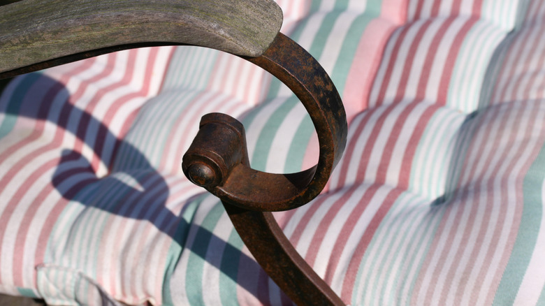A close-up image of an outdoor patio chair shows rust on the metal arm.