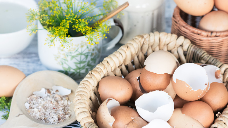 A basket of  eggs and eggshells is on a table.