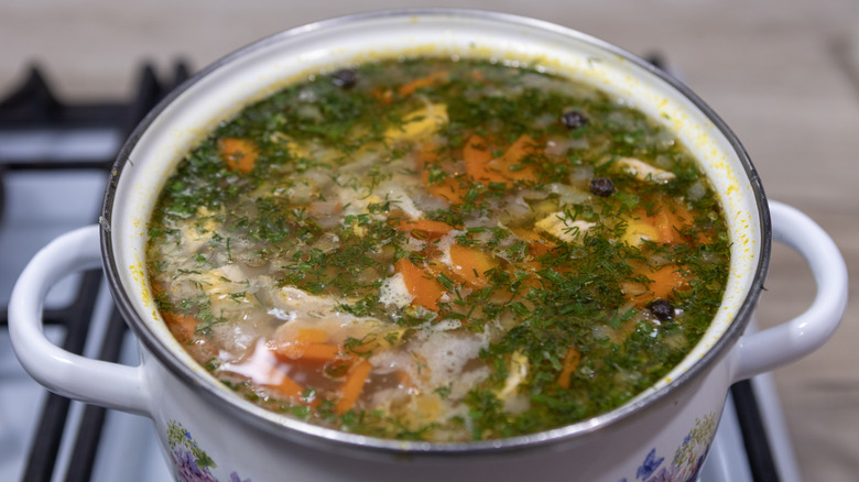 Vegetables and herbs cook in a pot.